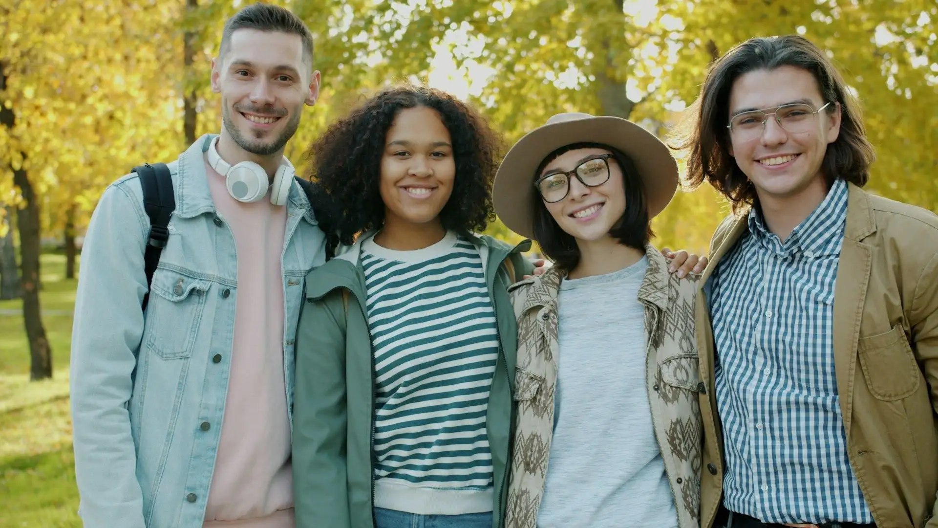 Four friends standing together among golden autumn trees