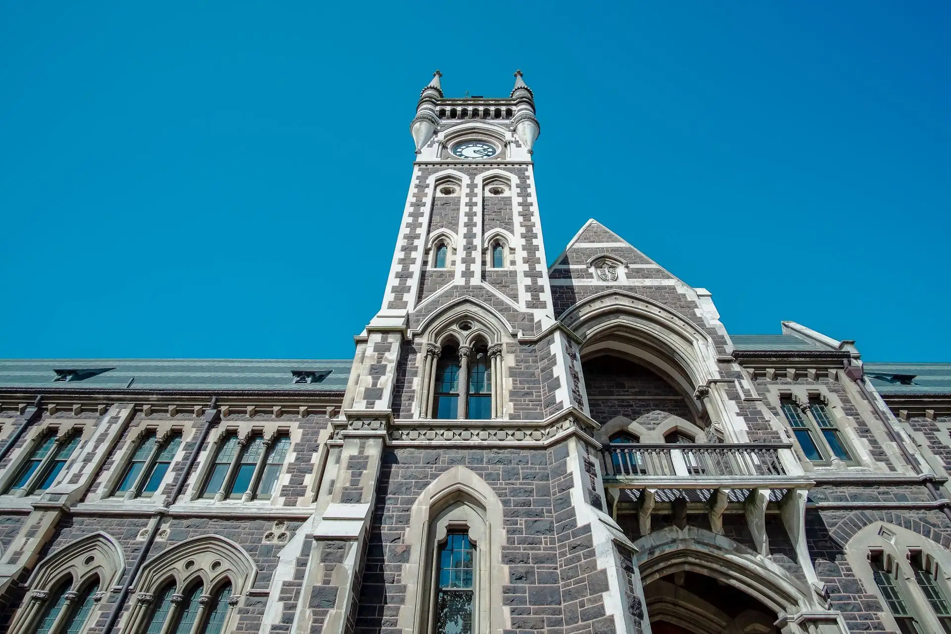 The ornate bluestone clocktower of the University of Otago against a deep blue sky
