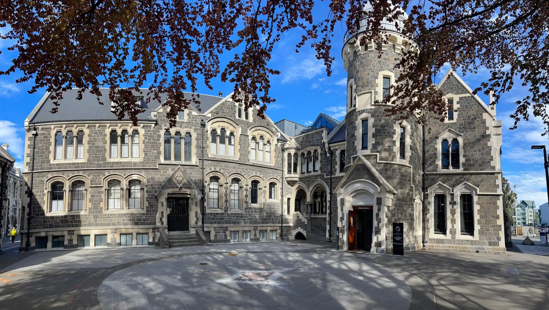 The stone Christchurch Arts Centre building under autumn trees
