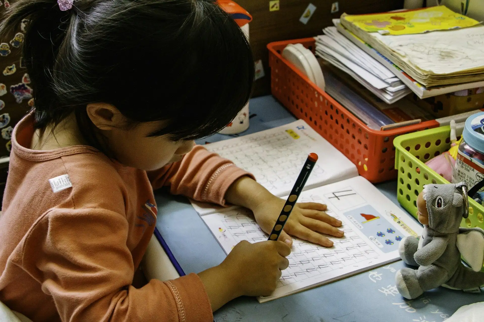 A young student drawing at a desk in a bright primary classroom