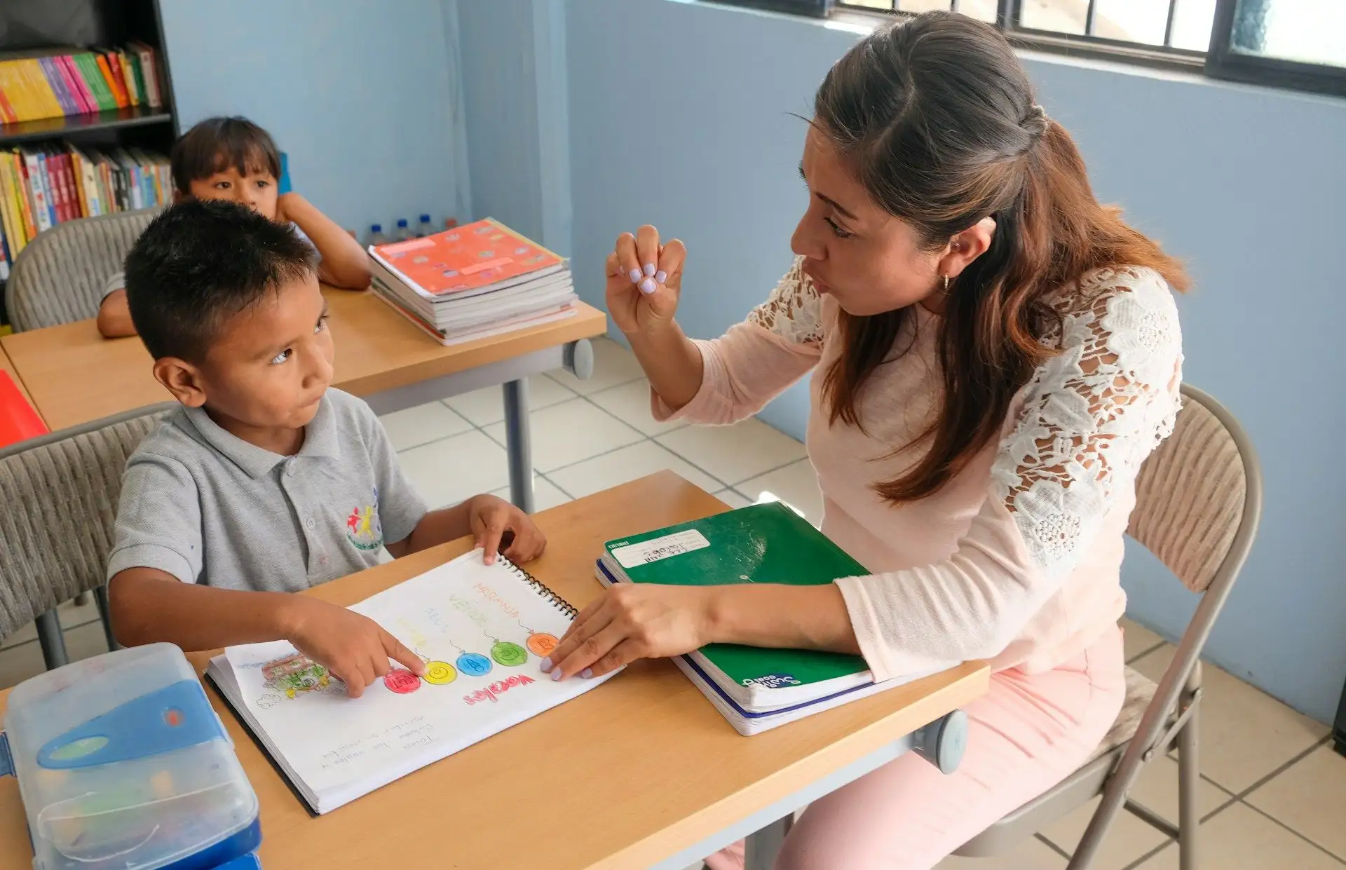 A teacher helping a young student at a desk