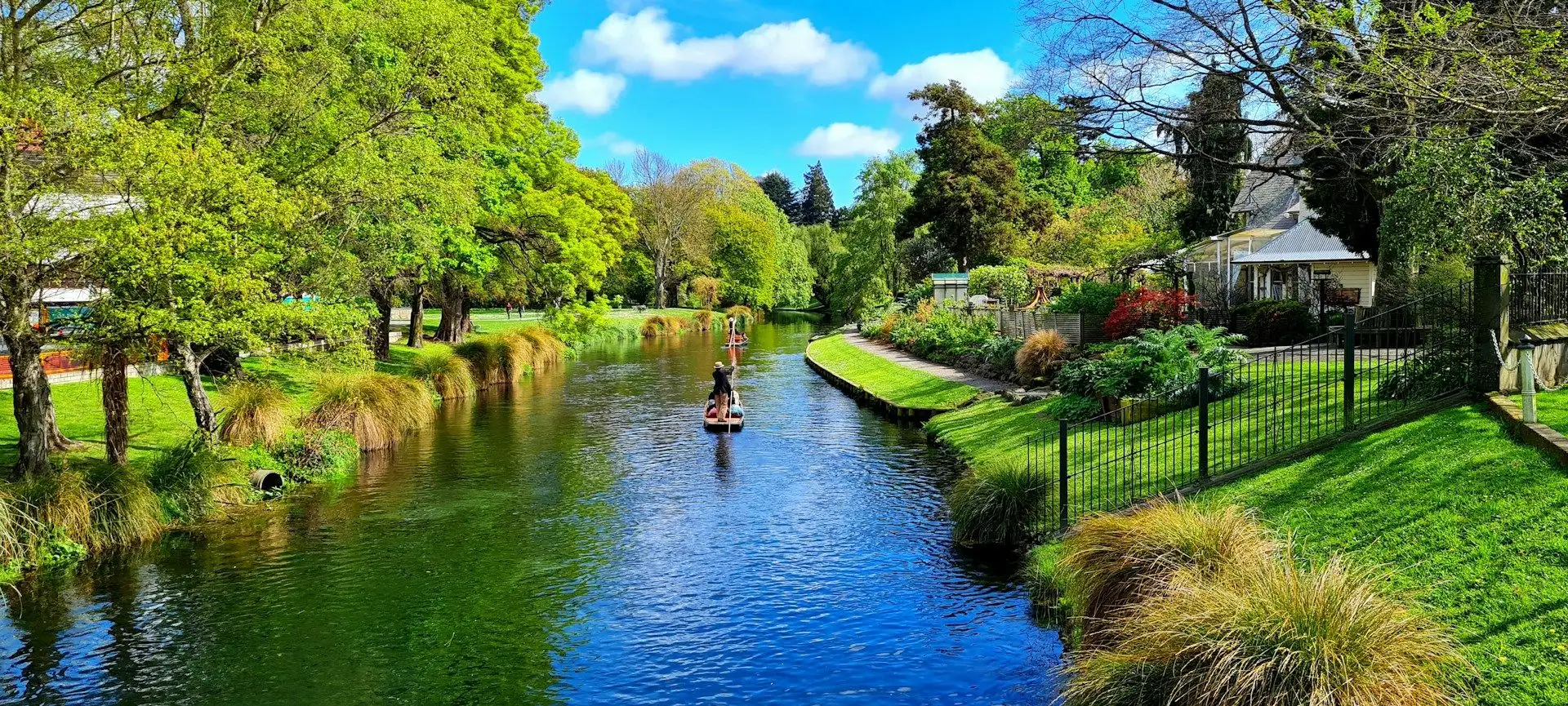 Punting on the Avon River through bright green gardens in Christchurch
