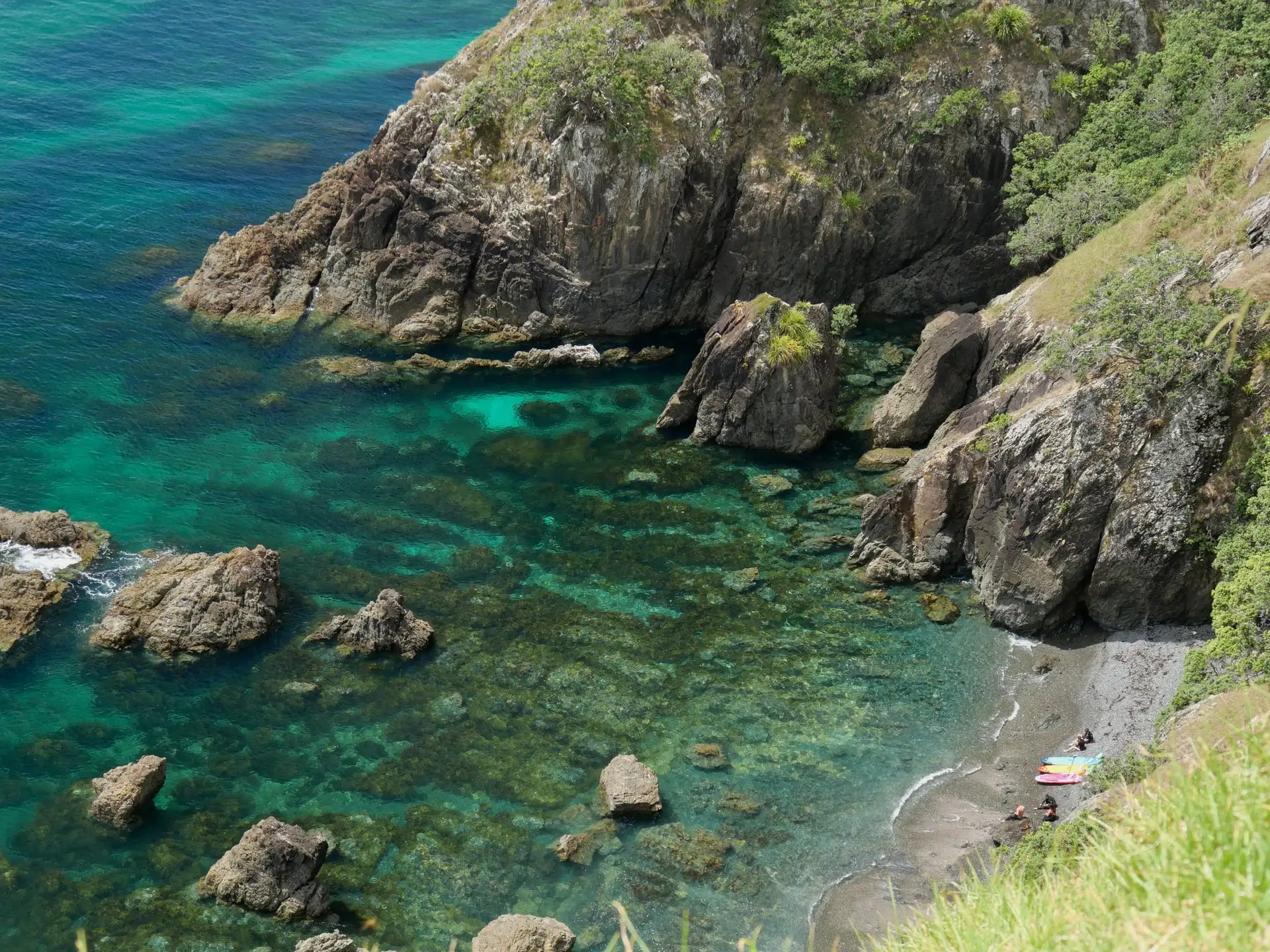 A rocky cove with emerald water seen from above