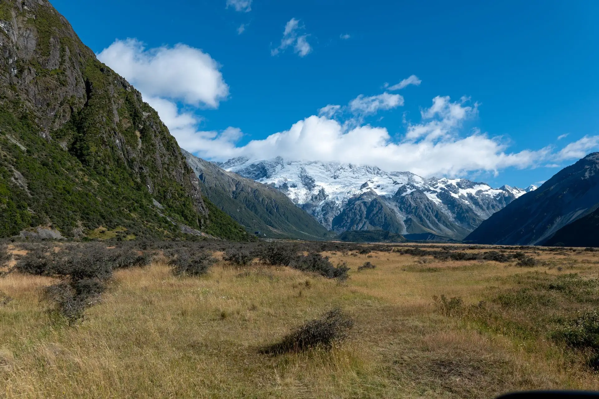 Aoraki/Mount Cook's snowy valley under a blue sky with big clouds