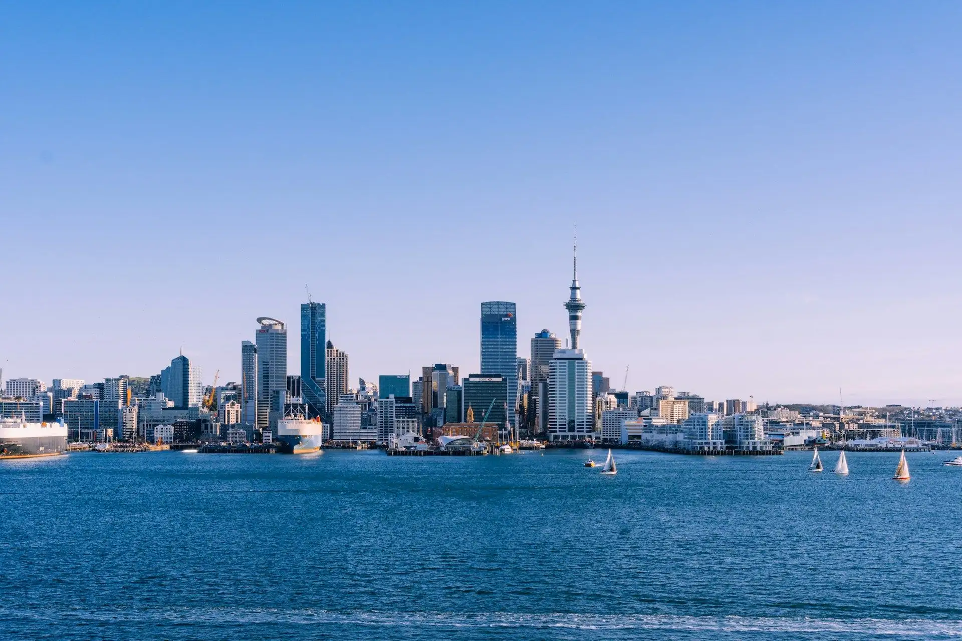 The Auckland skyline and Sky Tower across blue harbour water