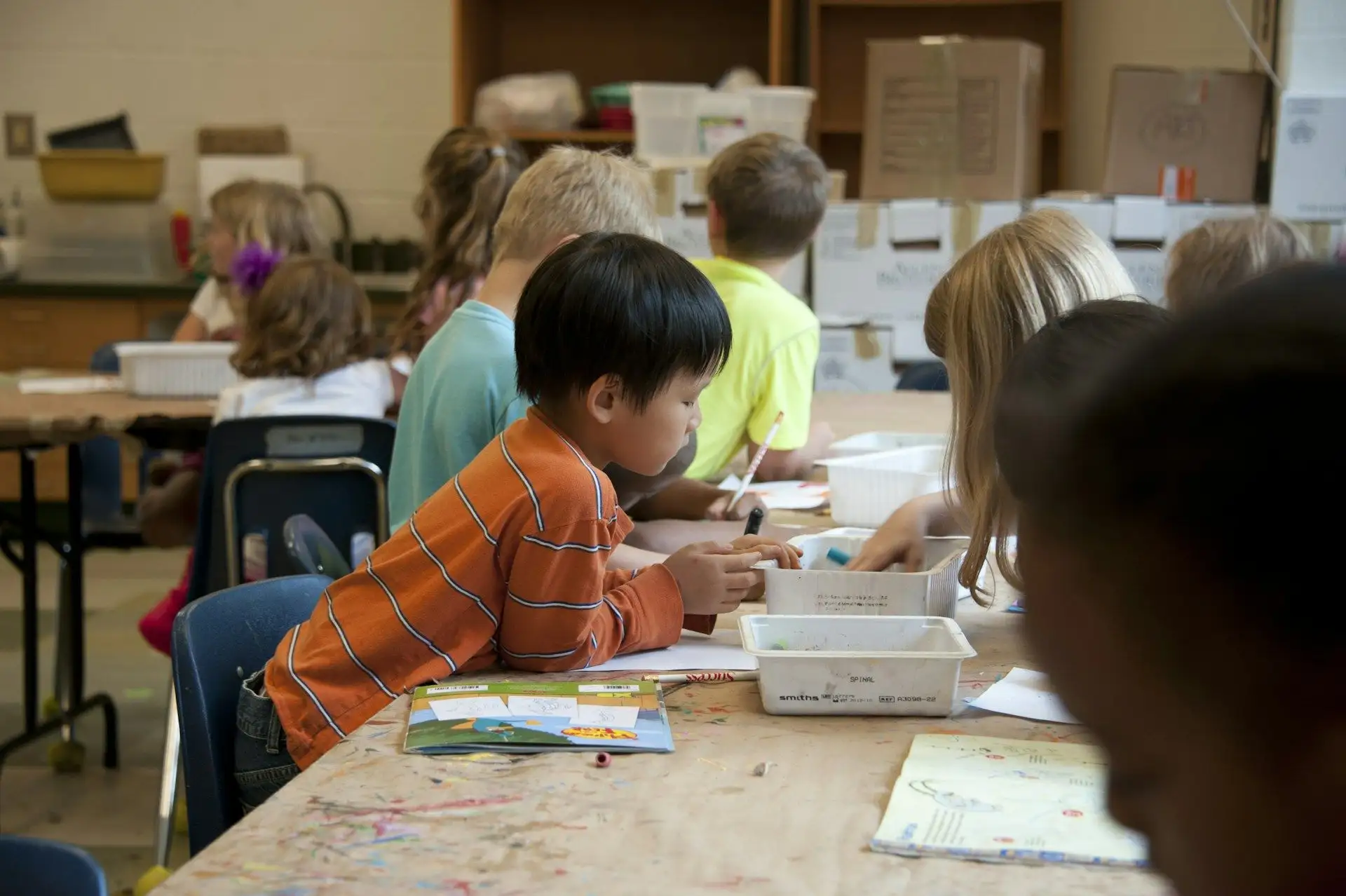 Primary students working at tables in a busy classroom