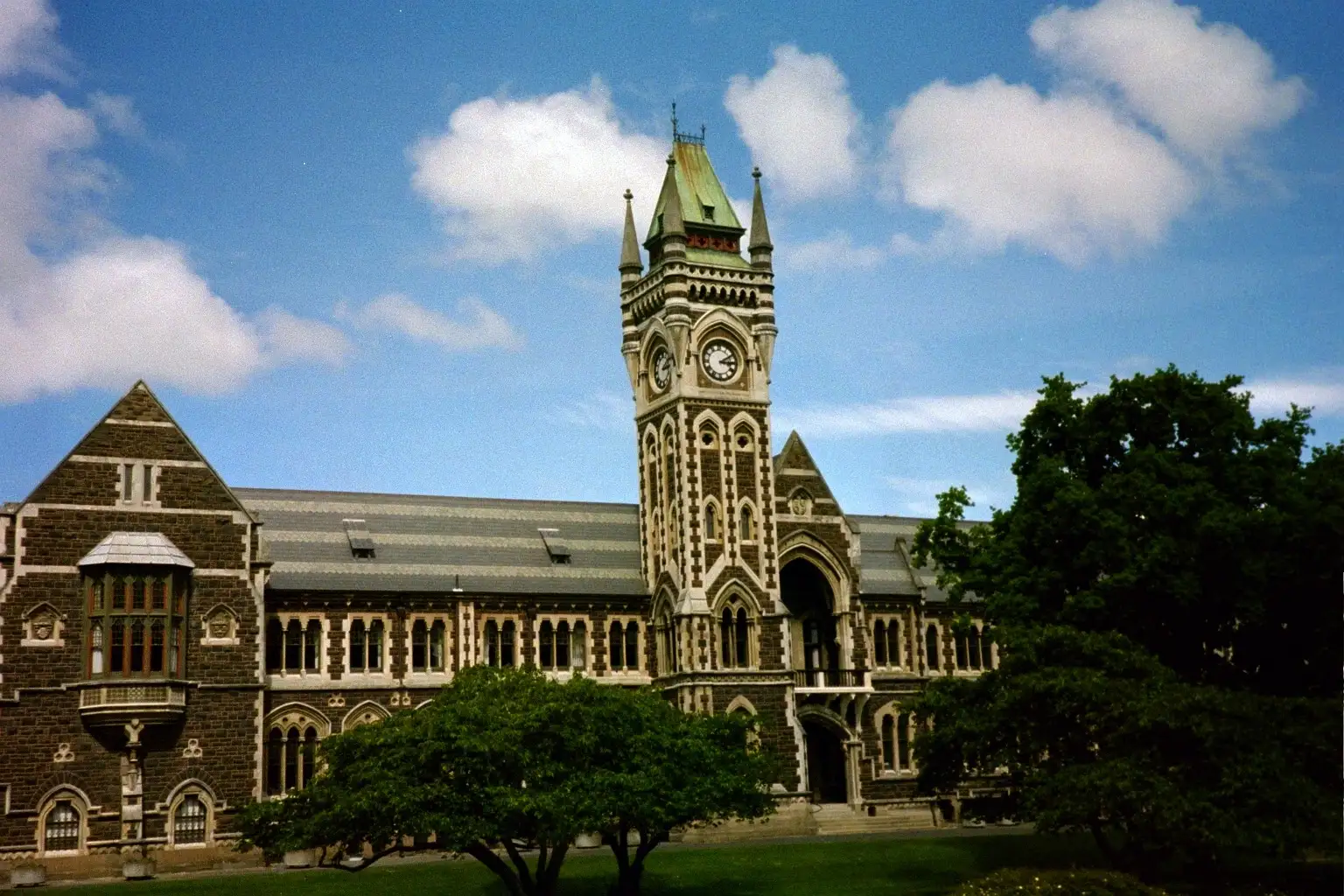 Historic stone Clocktower building at the University of Otago framed by campus trees