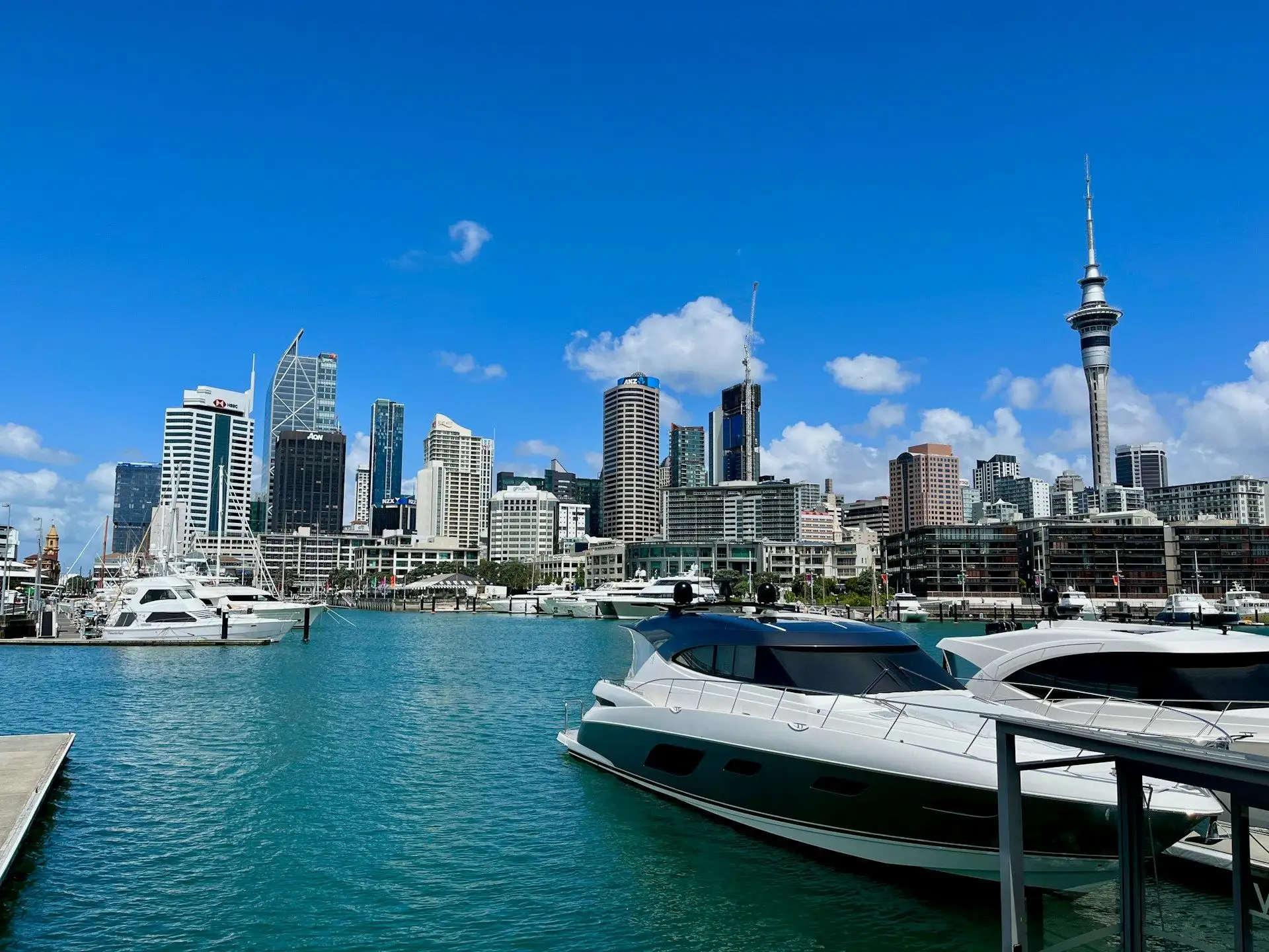 Superyachts at Viaduct Harbour with the Auckland skyline under a blue sky