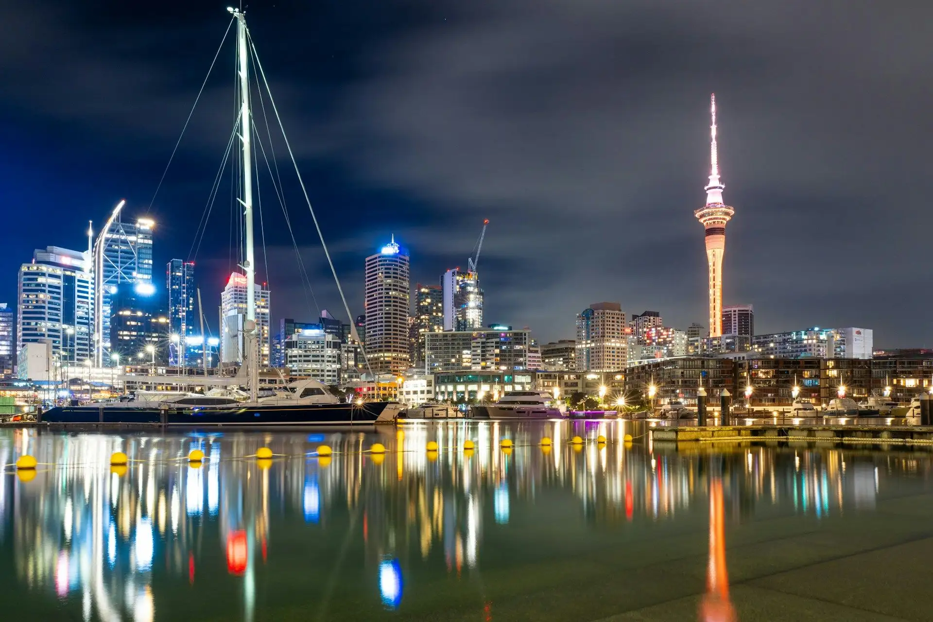 Viaduct Harbour's masts and the Sky Tower reflected at night