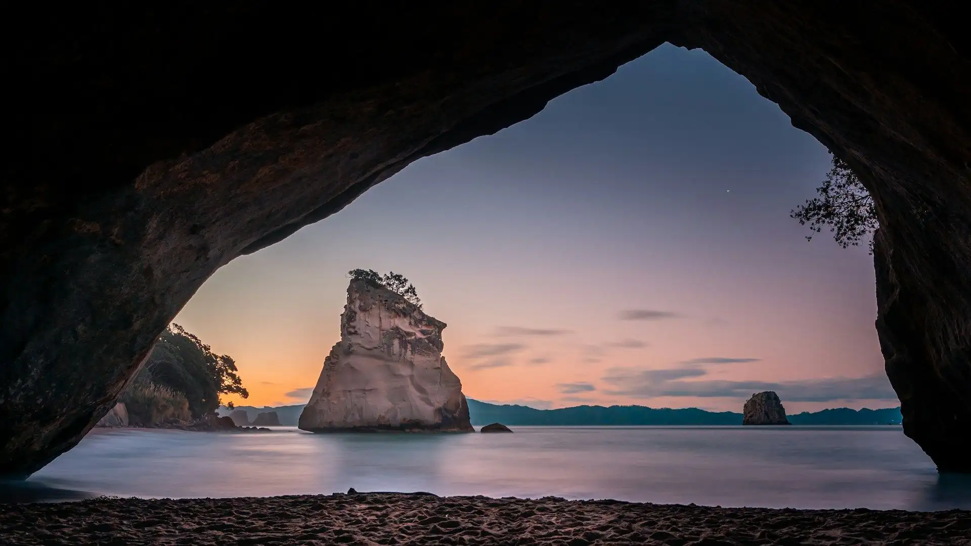 The Cathedral Cove arch at dusk with a pink and orange sky