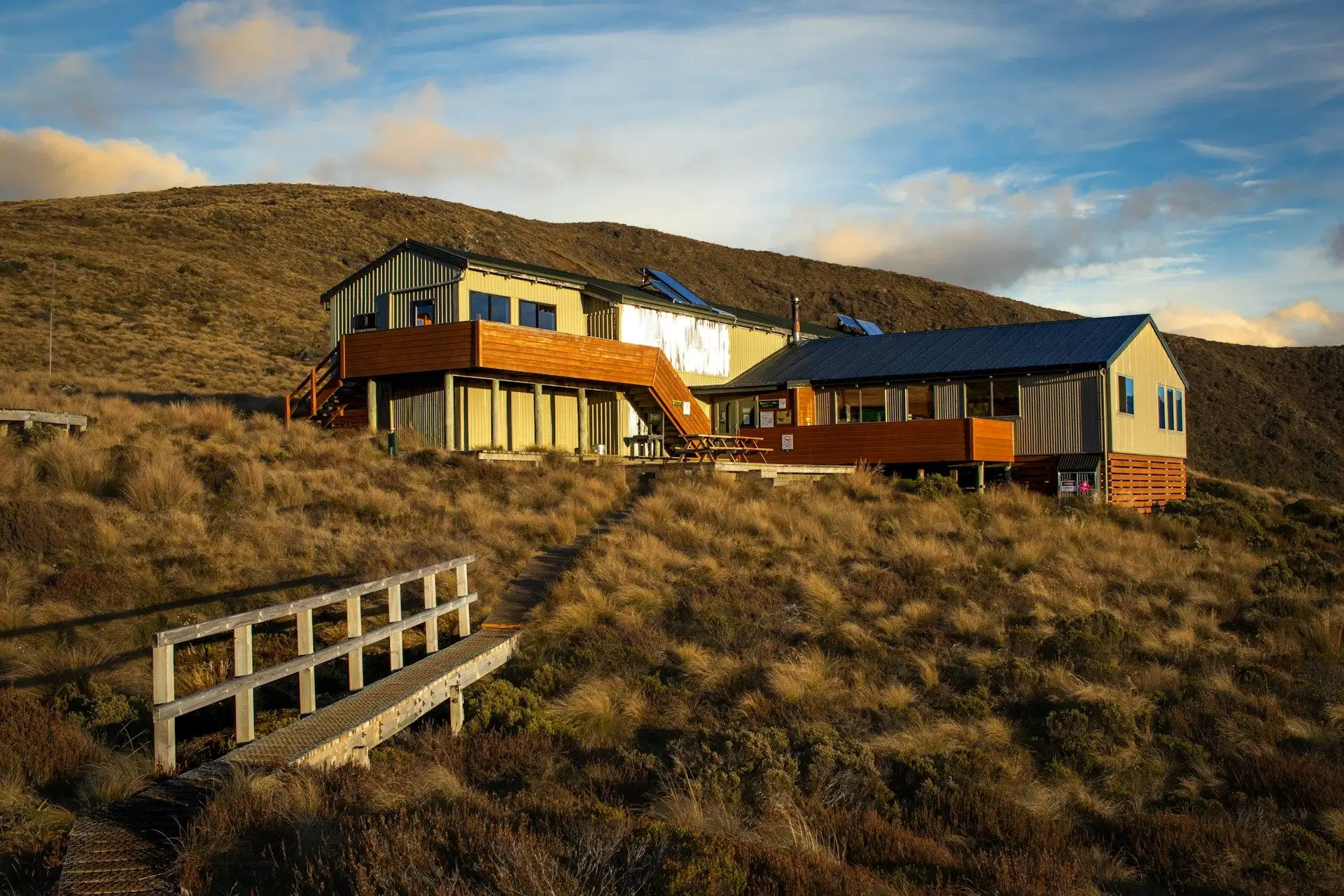 A contemporary lodge on golden tussock hills in evening light
