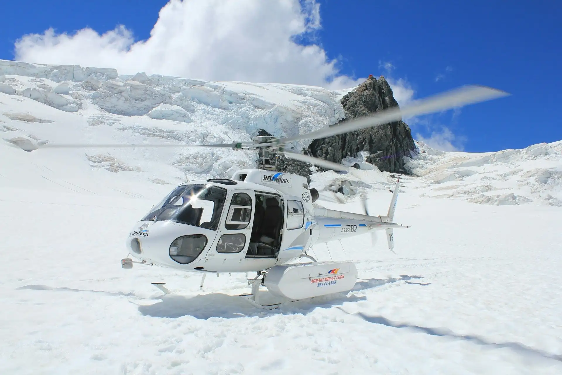 A helicopter parked on a glacier snowfield under a deep blue sky