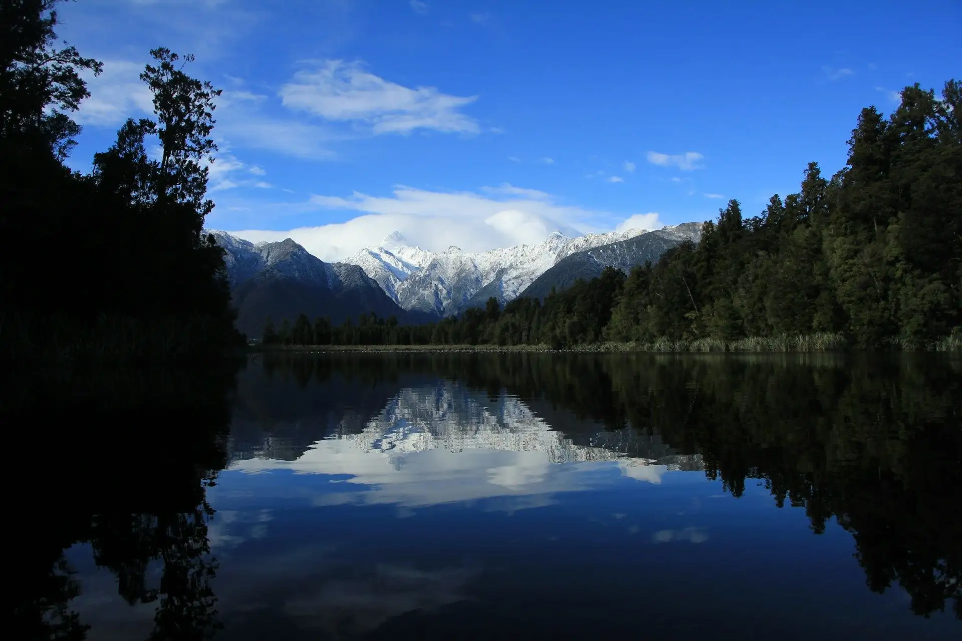 Snow peaks and blue sky reflected in Lake Matheson