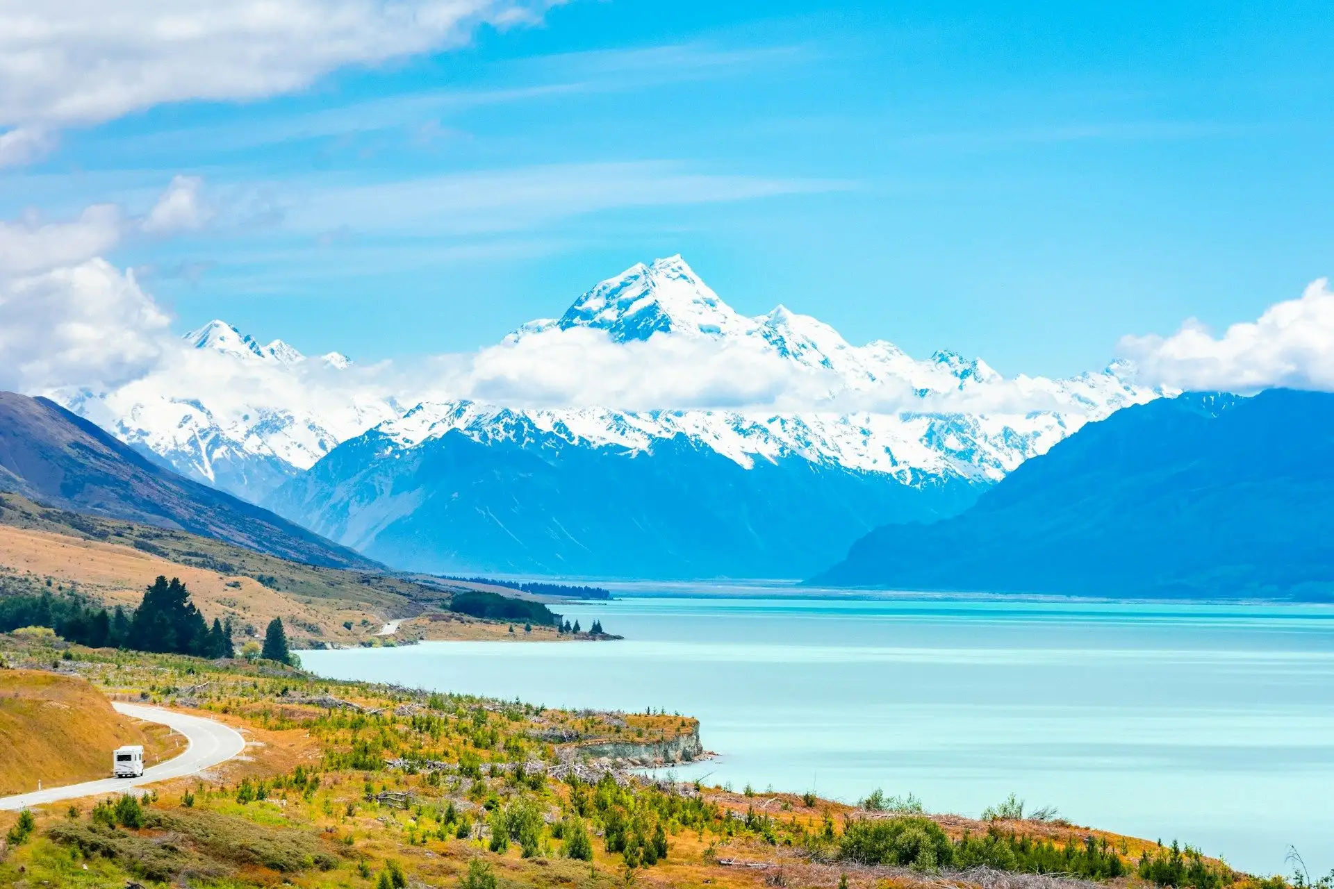 Turquoise Lake Pukaki below snow-covered Aoraki/Mount Cook, with the road curving beside it