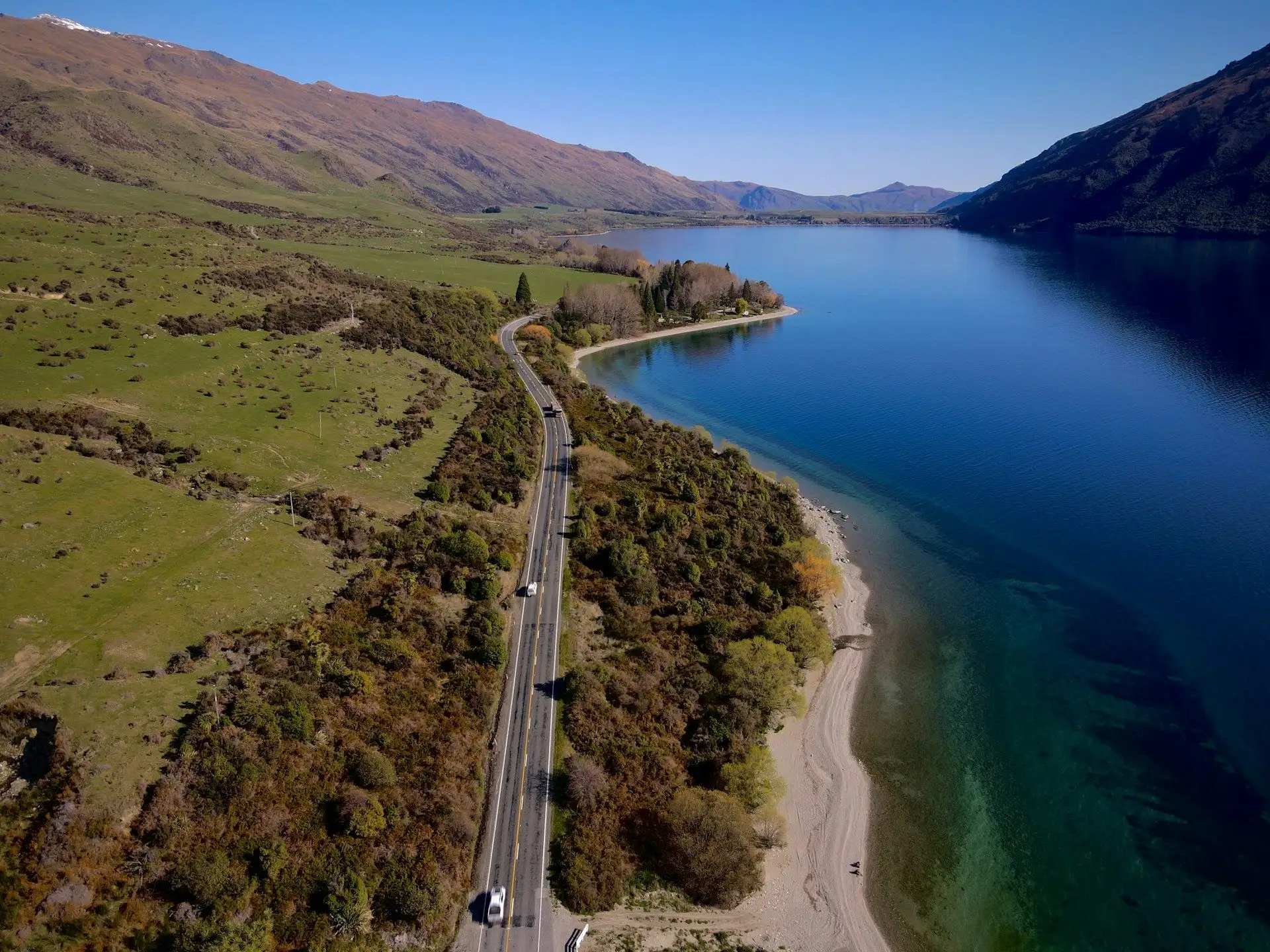 A lakeside road beside deep blue water near Wanaka, seen from above